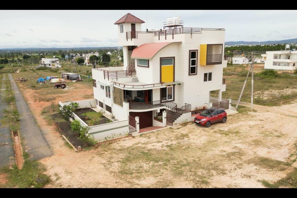 ein Haus mit einem roten Auto, das davor geparkt ist in der Unterkunft Shobha Comforts in Chikmagalur