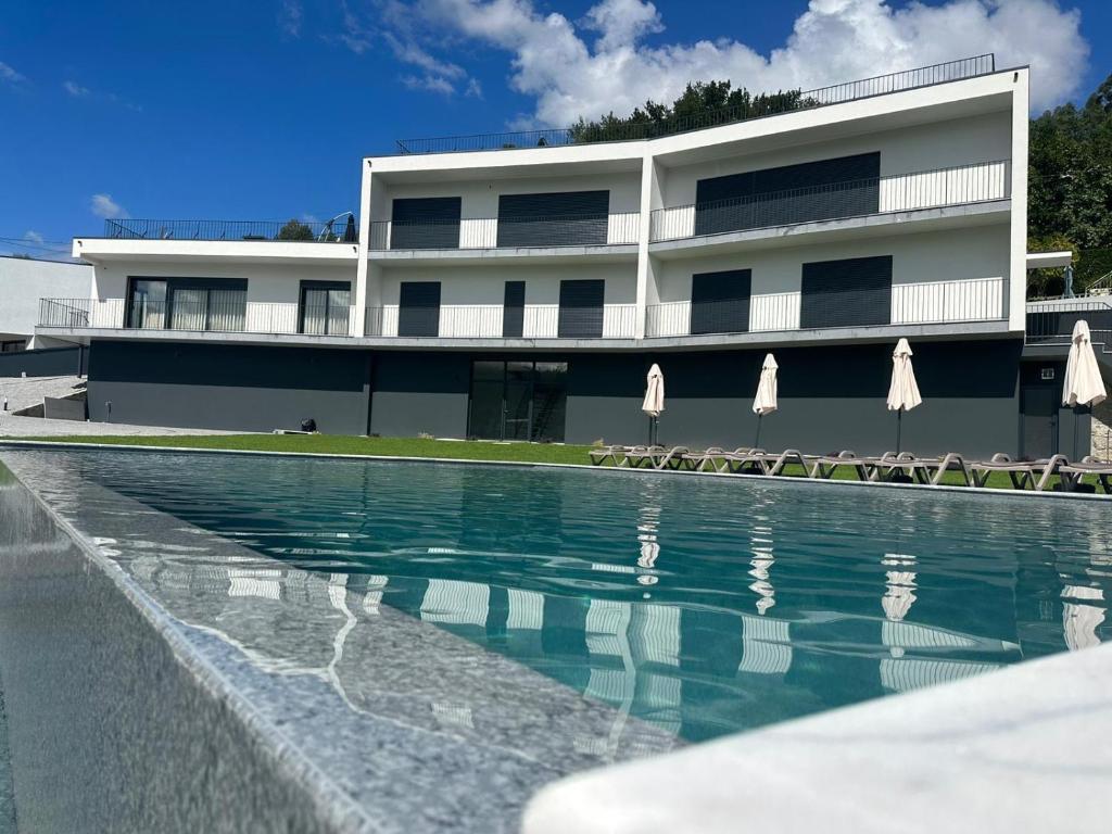 einem Pool vor einem Gebäude mit Sonnenschirmen in der Unterkunft Ermal Terrace in Vieira do Minho