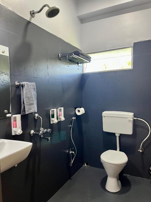 a bathroom with a white toilet and a sink at Bhūma in Havelock Island
