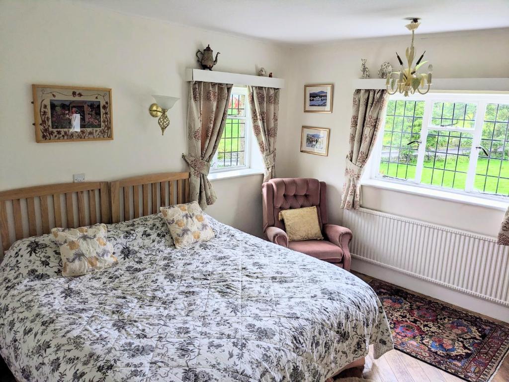 a bedroom with a bed and a chair and windows at Thornley House in Hexham
