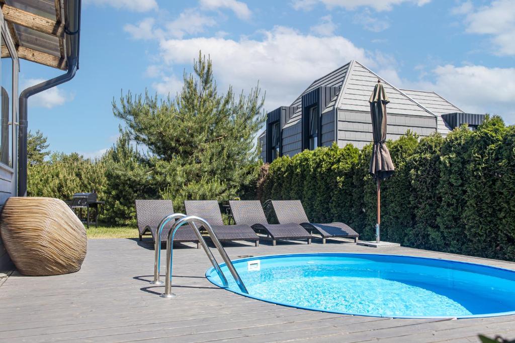 a swimming pool on a deck with chairs and an umbrella at Villa with private pool Laumes juosta in Palanga