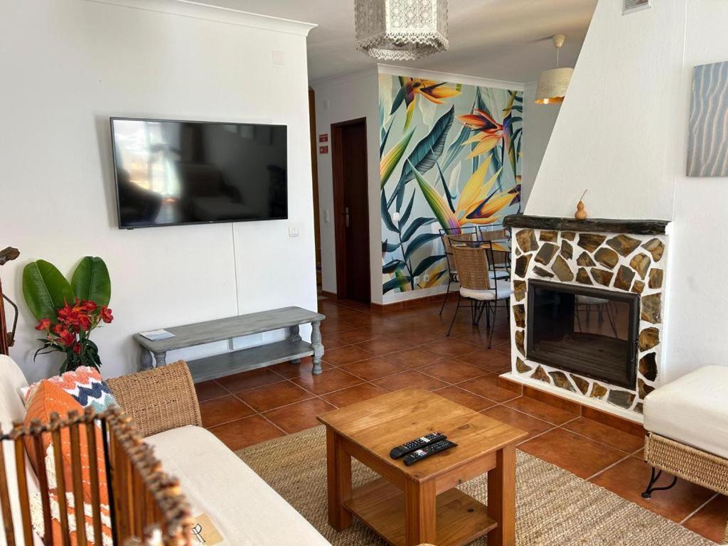 a living room with a fireplace and a tv at Casa com Cor in Zambujeira do Mar