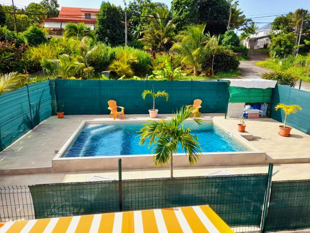 einen Pool mit zwei Stühlen und einem Zaun in der Unterkunft Maison d'une chambre avec piscine partagee terrasse amenagee et wifi a Petit Bourg in Petit-Bourg