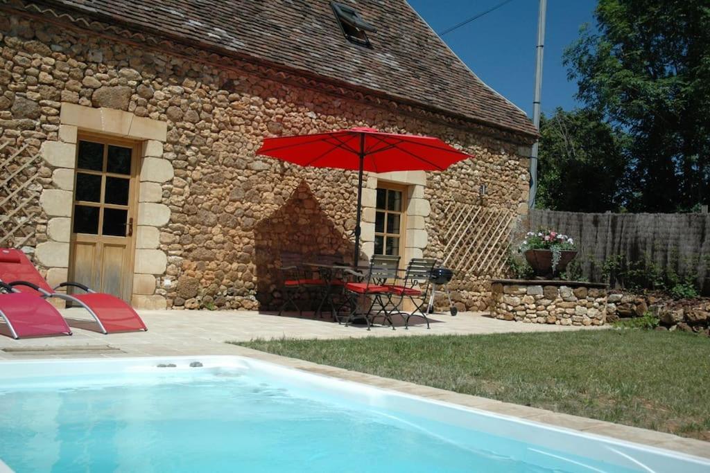 un parapluie rouge à côté d'une maison avec piscine dans l'établissement Belle grange du 18ème restaurée avec charme, à Rouffignac-Saint-Cernin-de-Reilhac