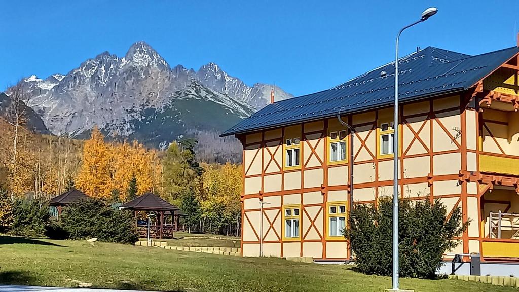 a large building with mountains in the background at Vila Kollár Apartmán Rosa 14 in Vysoké Tatry