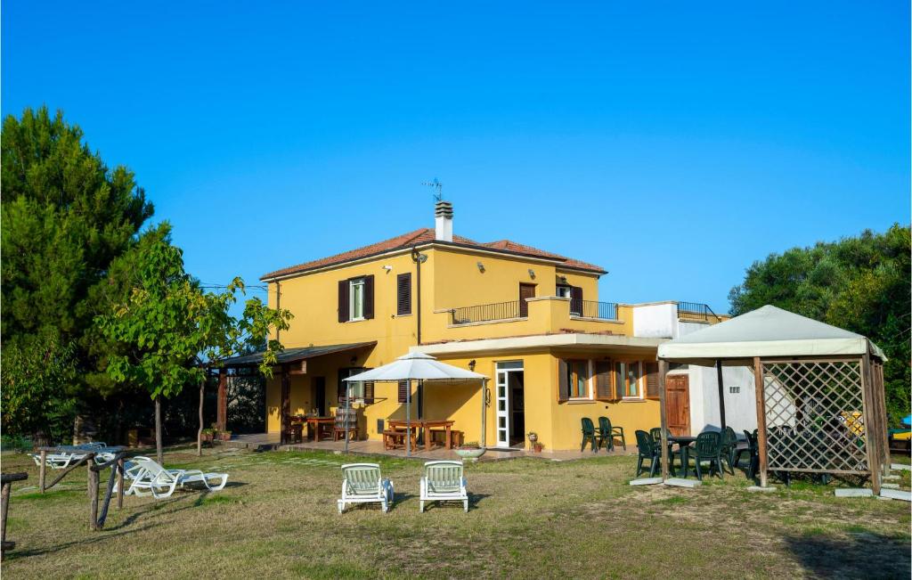 a yellow house with chairs and tables in front of it at Amazing Home In Roseto Degli Abruzzi With Kitchen in Roseto degli Abruzzi