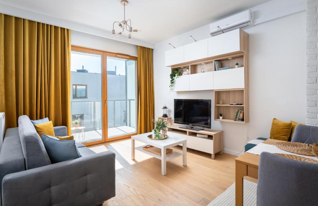 a living room with a couch and a tv at Białego Dębu Cosy Apartment in Warsaw