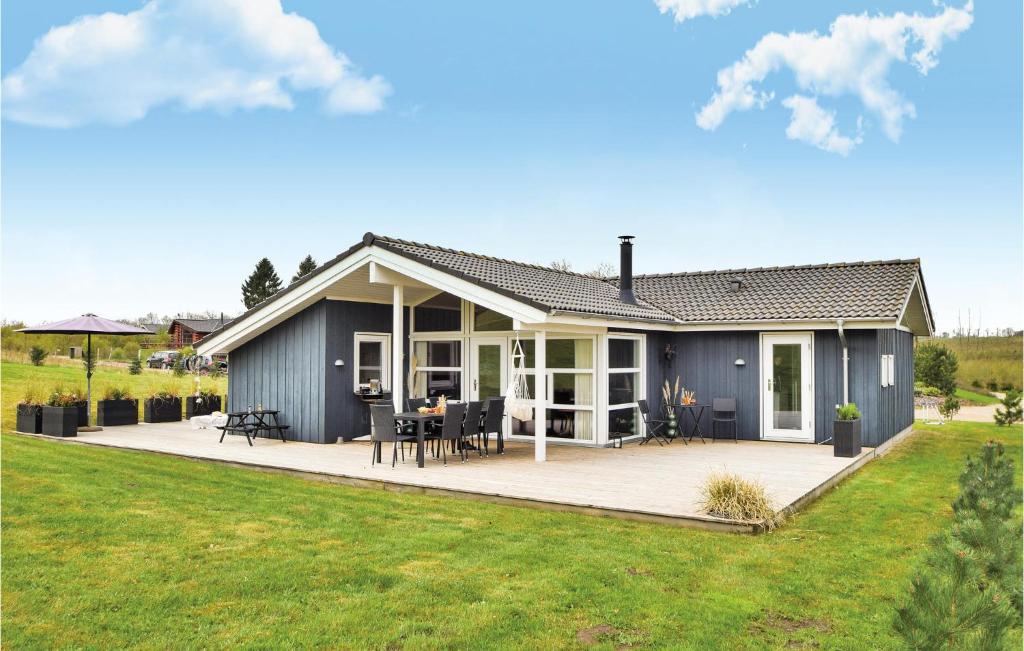 una casa azul con terraza y césped en 4 Bedroom Nice Home In Ejstrupholm, en Krejbjerg
