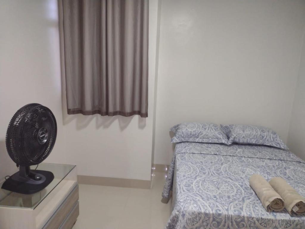 a bedroom with a bed with a fan and a window at Lindo apto praia do bessa in João Pessoa