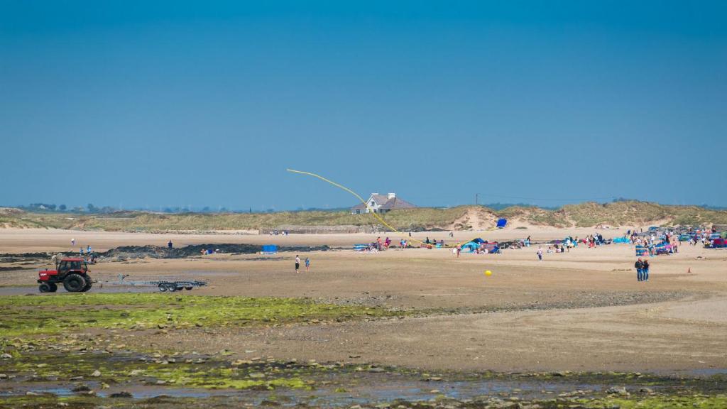 a group of people on a beach with a kite at Bro Dawel in Rhosneigr