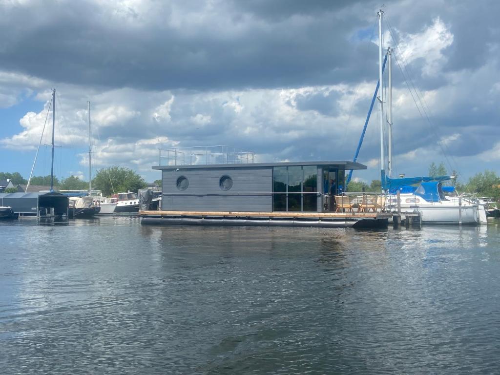 un barco está atracado en un muelle en el agua en La Mare Houseboat, en Nederhorst den Berg