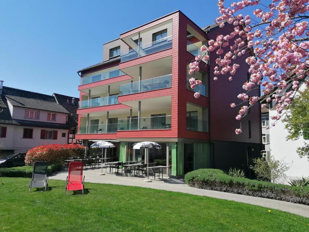 ein rotes Gebäude mit Stühlen und Tischen im Gras in der Unterkunft Ferienhotel Bodensee in Berlingen