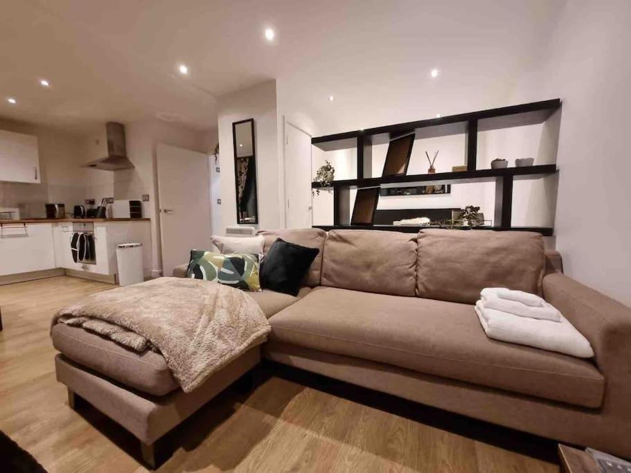 a living room with a brown couch and a kitchen at Charming studio in Bricklane in London