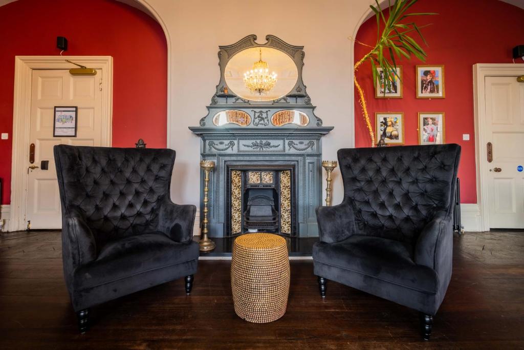 a living room with two chairs and a fireplace at Palmers Lodge Swiss Cottage in London