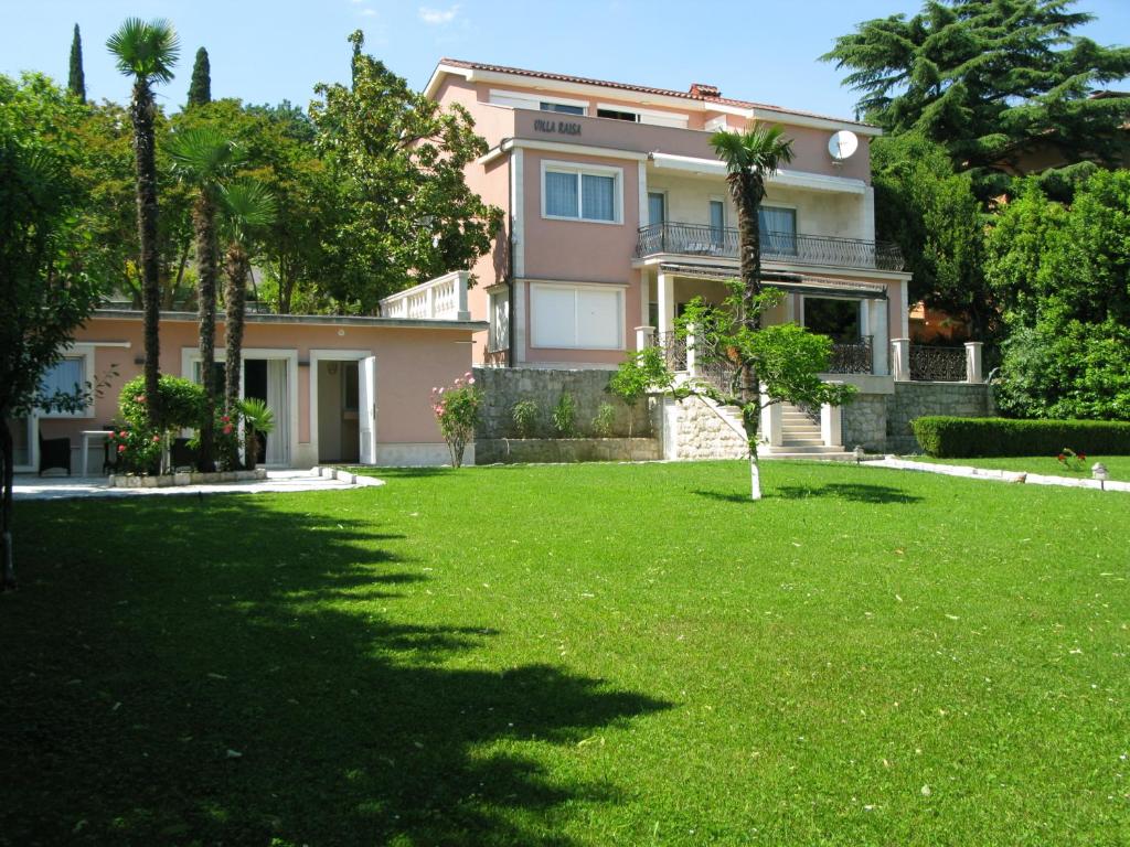 una casa con un césped verde delante de ella en Villa Raisa, en Opatija