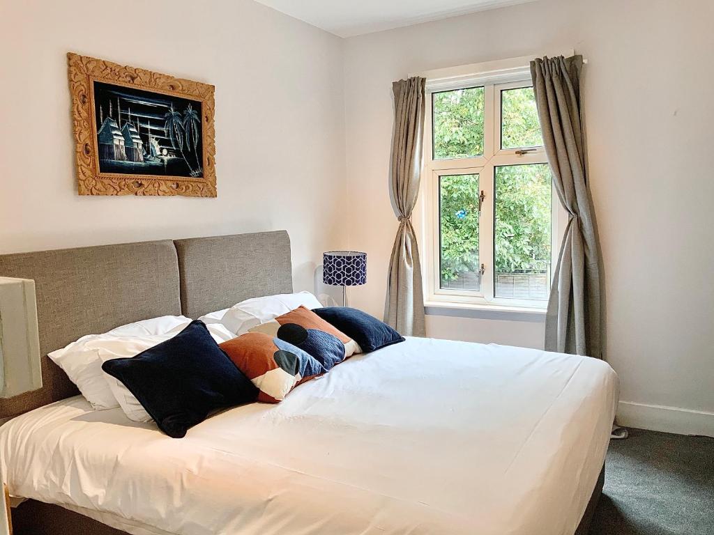 a bedroom with a bed with white sheets and a window at Lovely 2BR Cottage in Stansted in Stansted Mountfitchet