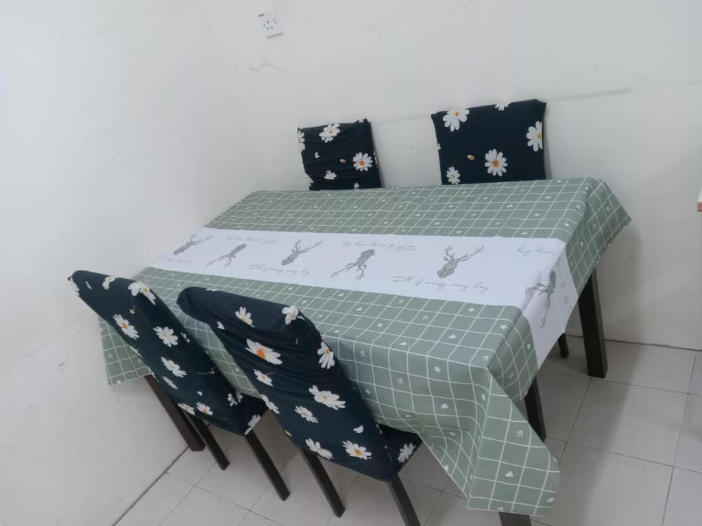 einen Tisch mit 2 Stühlen und einen Tisch mit einem grünen und weißen Tischtuch in der Unterkunft NORIS GUEST HOUSE 2 in Gambang