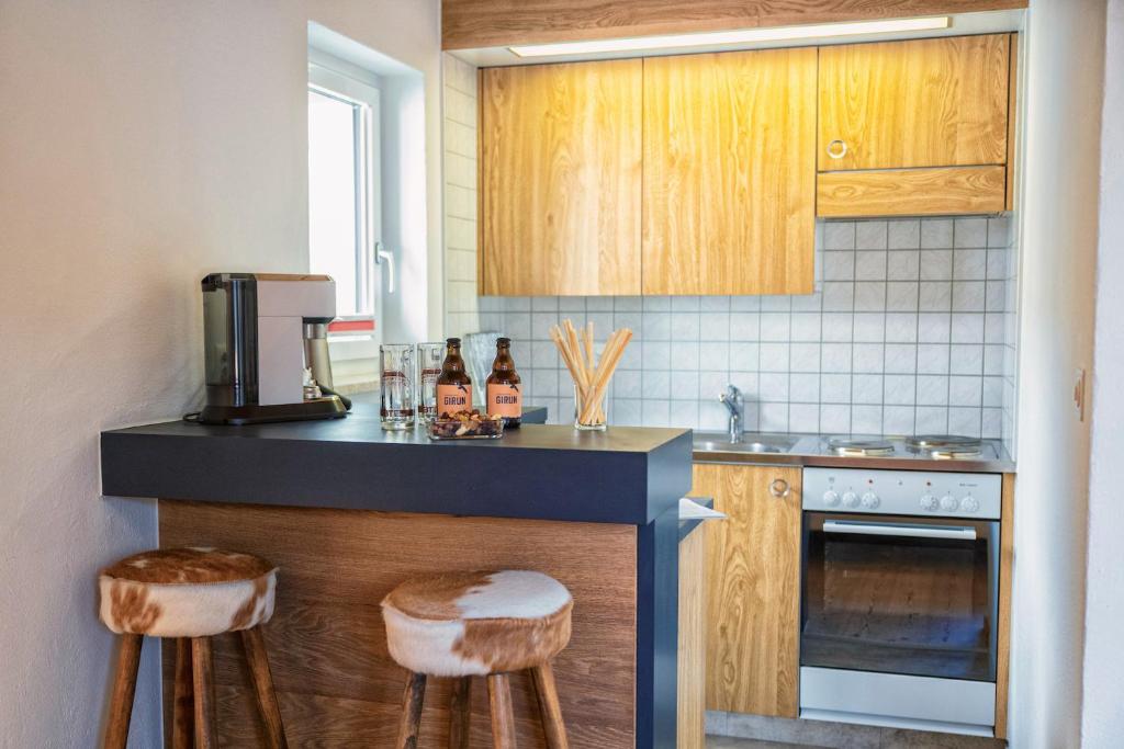 施庫爾的住宿－Chasa Gisep，厨房配有木制橱柜和带凳子的台面