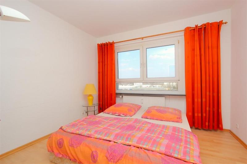 a bedroom with a bed with orange curtains and a window at Private Rooms in Hannover
