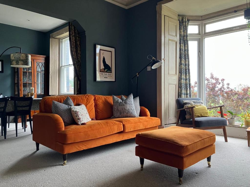 勒德洛的住宿－Kennet House，客厅里设有一张橙色的沙发,拥有蓝色的墙壁