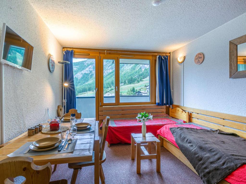 - une chambre avec une table, un lit, une table et des chaises dans l'établissement Studio sud au pied des pistes, balcon et animaux acceptés - FR-1-694-209, à Val dʼIsère