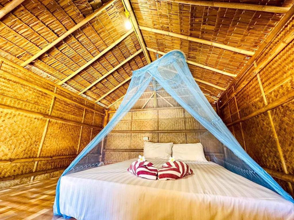 a bed in a straw hut with a mosquito net at Check in Lanta in Ko Lanta
