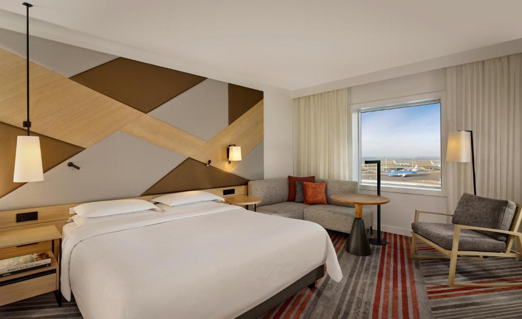 una camera d'albergo con letto, scrivania e finestra di Sheraton Amsterdam Airport Hotel and Conference Center a Schiphol