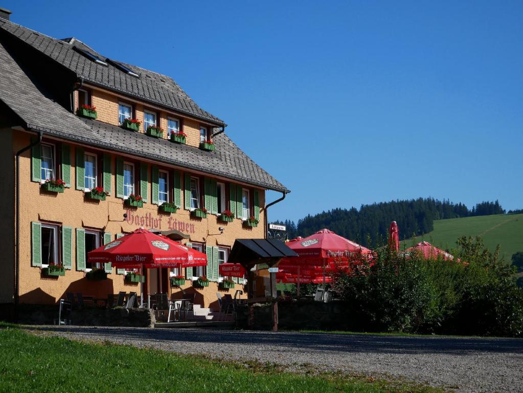 ein Gebäude mit roten Sonnenschirmen davor in der Unterkunft Feriengasthof Löwen in Breitnau