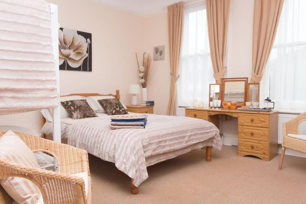 Schlafzimmer mit einem Bett, einem Schreibtisch und einem Spiegel in der Unterkunft The Bournemouth Villa by the Sea, sleeps 26 in Bournemouth