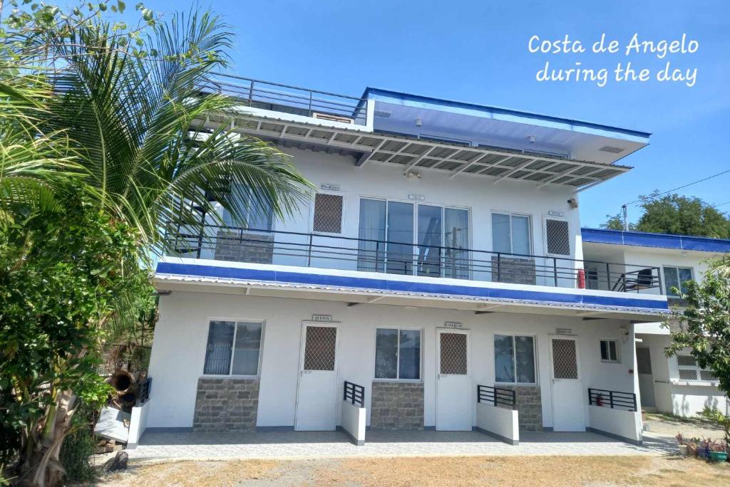 a white house with a balcony and a palm tree at COSTA DE ANGELO BOLO BEACH RESORT in Alaminos