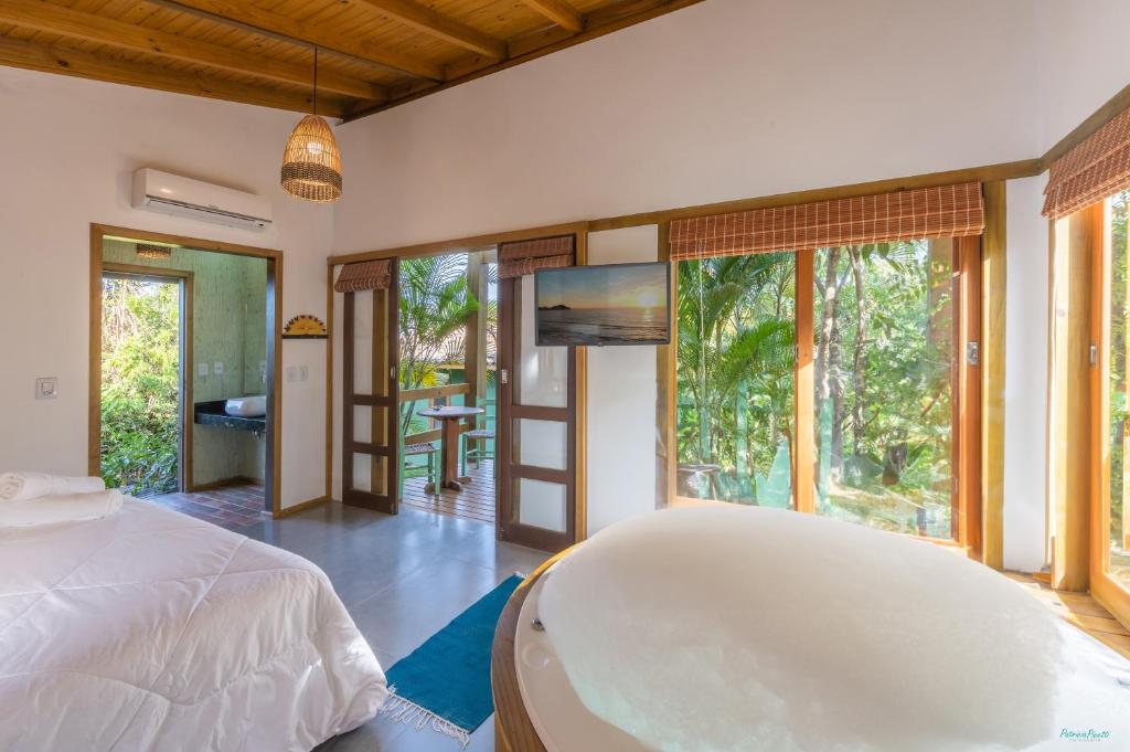 a bedroom with a large bed and a tub in it at Pousada Watu Kerere in Praia do Rosa