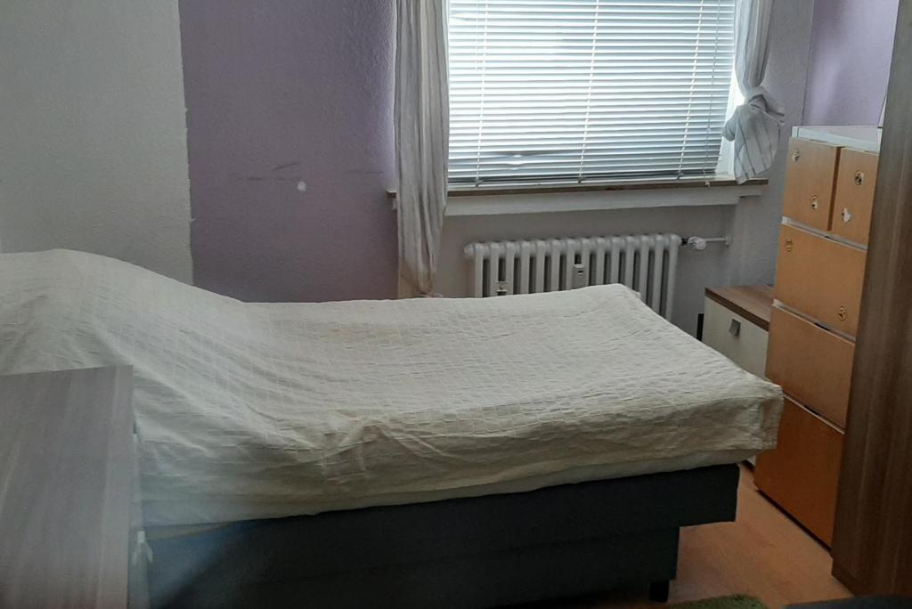 niewielka sypialnia z łóżkiem i oknem w obiekcie Private Rooms w Hanowerze