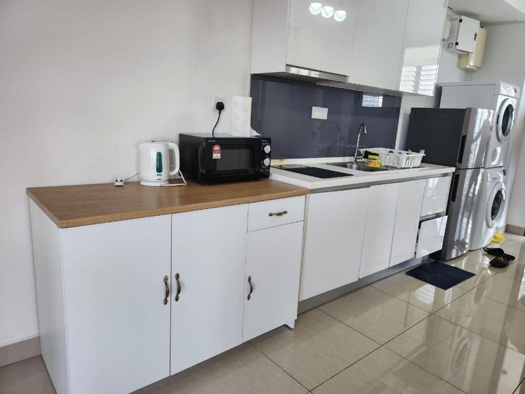 a kitchen with white cabinets and a counter top at Wanda Guest House Eclipse Cyberjaya in Cyberjaya