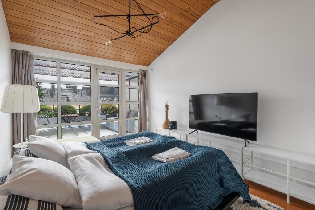 um quarto com uma cama e uma televisão de ecrã plano em WeHost Penthouse Studio with Sauna and Balcony @Meritullinkatu 13 A em Helsinque
