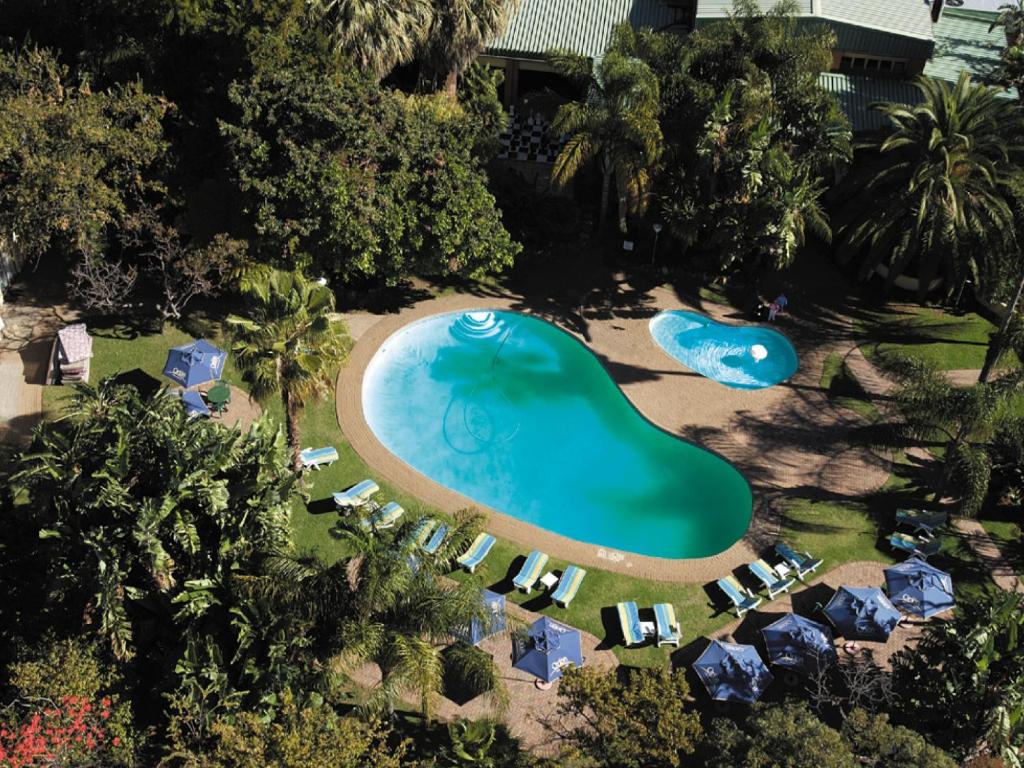 uma vista aérea de uma piscina de resort com guarda-sóis e cadeiras em Safari Hotel & Convention Centre em Rustenburg