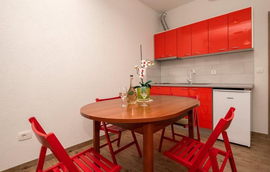eine Küche mit einem Holztisch und roten Stühlen in der Unterkunft Apartmani Valentina Drvenik in Drvenik