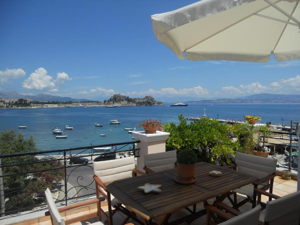 balcón con mesa, sillas y vistas al agua en Garitsa Bay Apartment, en Corfú