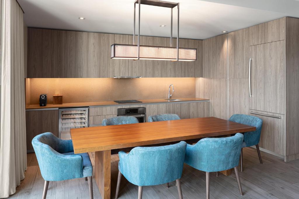 a kitchen with a wooden table and blue chairs at EAST Miami in Miami