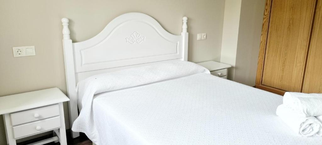ein weißes Bett mit einer weißen Tagesdecke und zwei Nachttischen in der Unterkunft Piso 2 Dormitorios. WIFI in Pontevedra