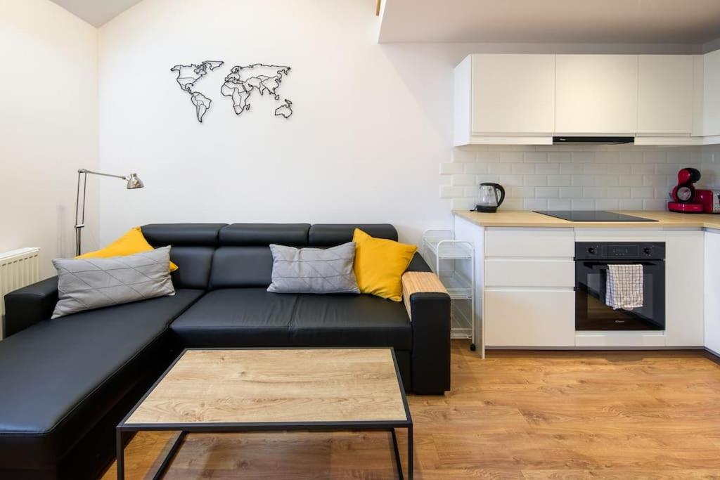sala de estar con sofá negro y cocina en Spacious and calm spot, en Cracovia