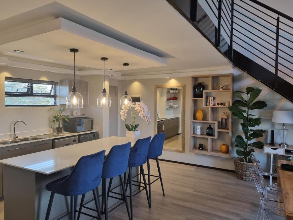 una cocina con sillas azules y una isla de cocina en Soho Luxury Penthouse, en Sandton