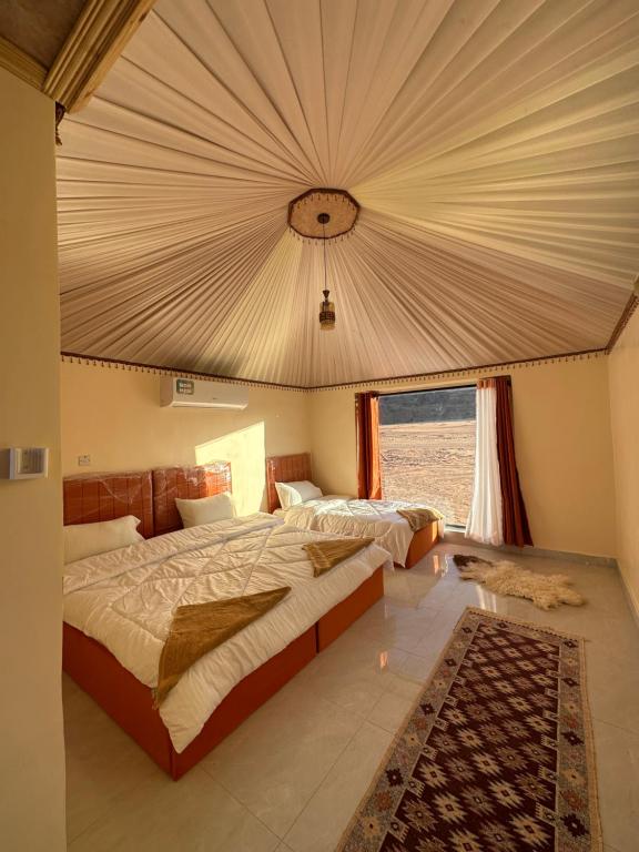 a bedroom with a large bed and a large window at Mountain Magic Camp Wadi Rum in Wadi Rum