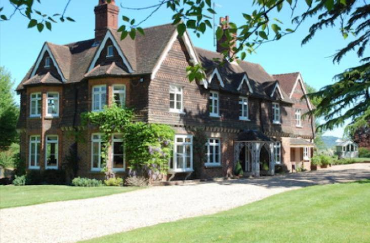 a large brown brick house with a large yard at Blackbrook House in Holmwood