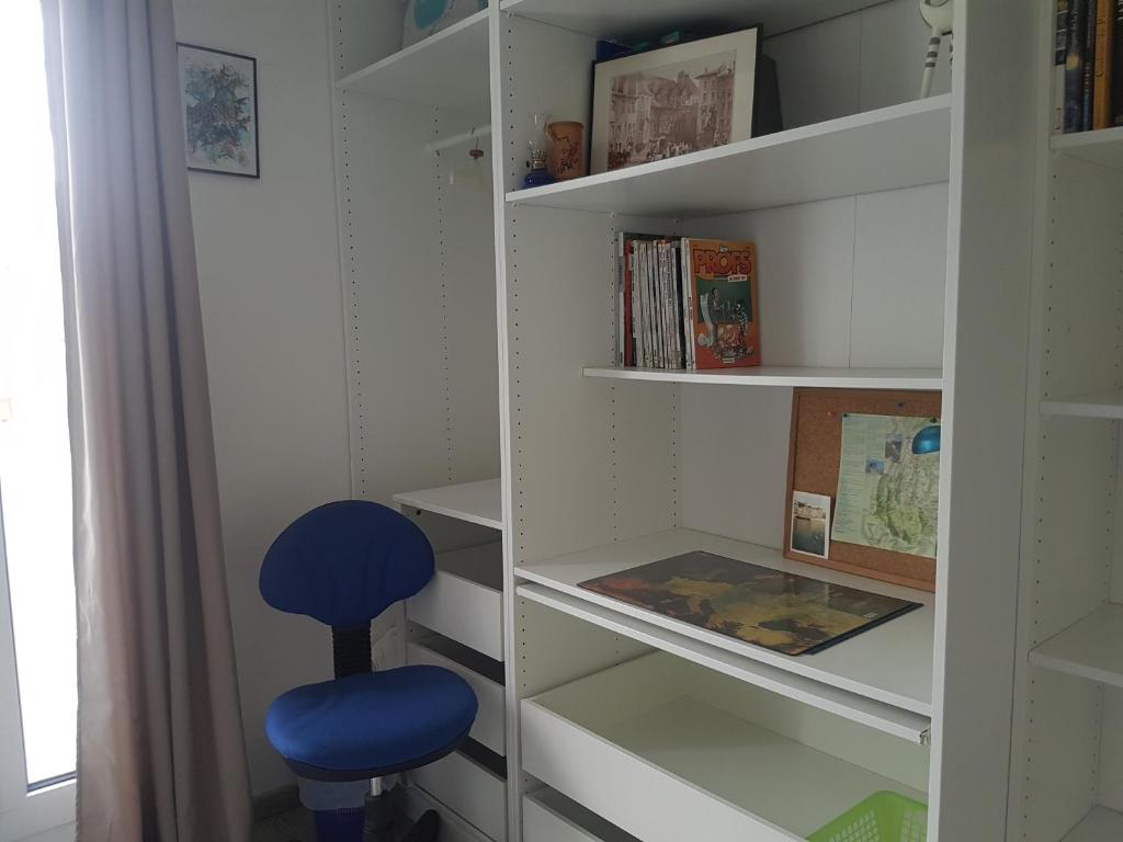 a blue stool sitting in a book shelf at Chambre chez l'habitant in Saint-Martin-dʼHères