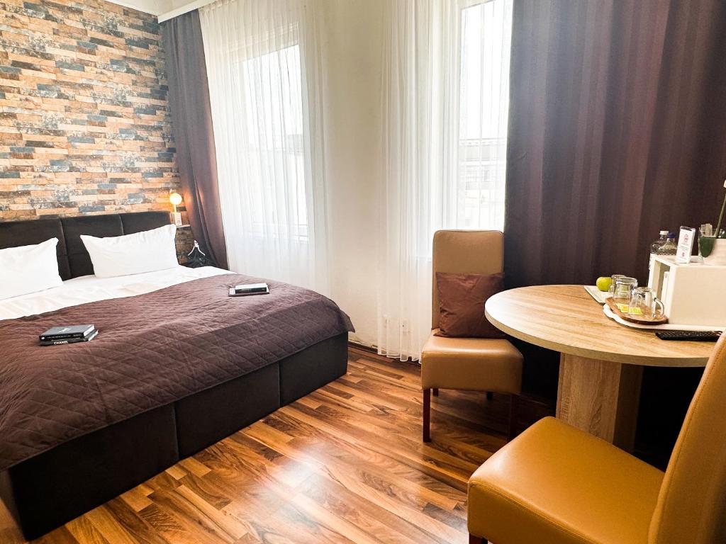 ein Schlafzimmer mit einem Bett und einem Tisch in einem Zimmer in der Unterkunft Hotel Condor in Hamburg