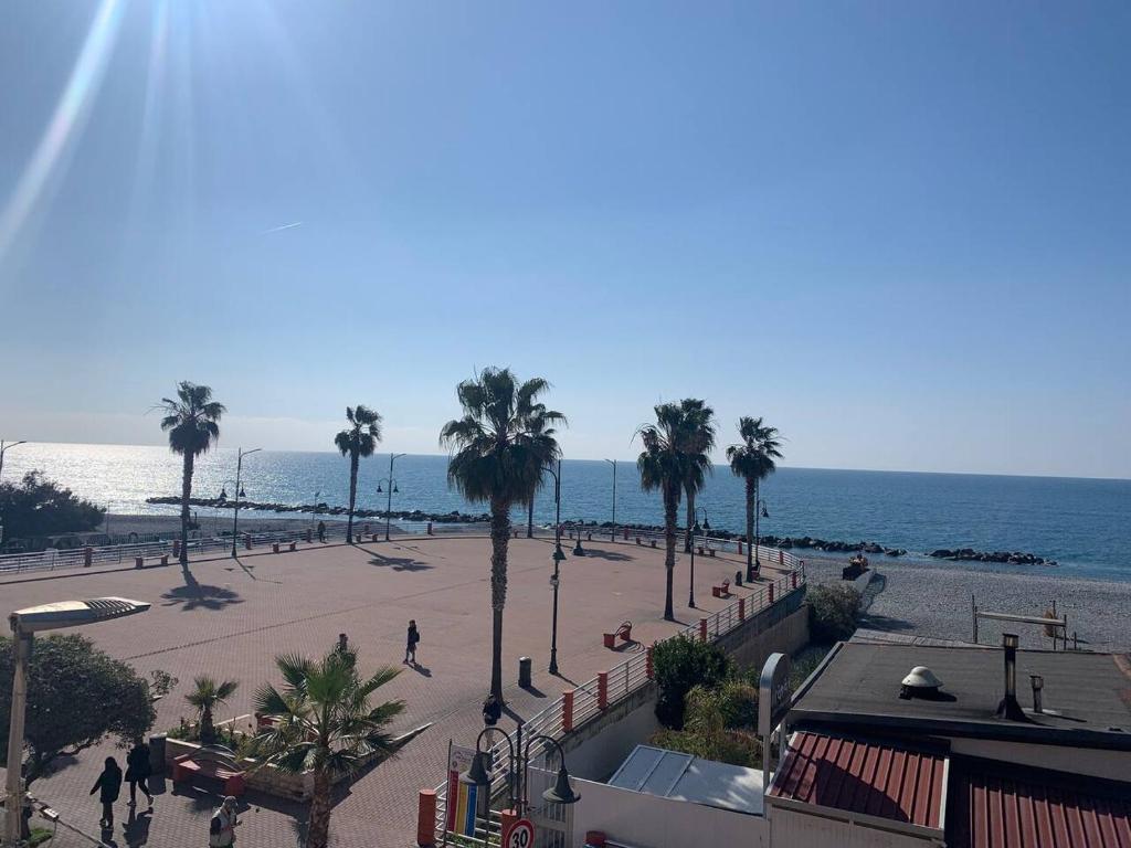een uitzicht op een strand met palmbomen en de oceaan bij Casa Vale fronte mare in Ventimiglia