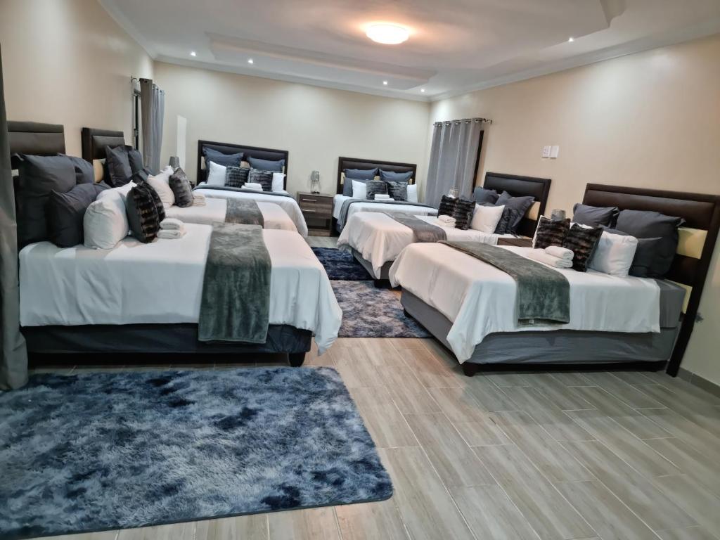 Un grupo de 4 camas en una habitación en Lasev Resort, en Pretoria