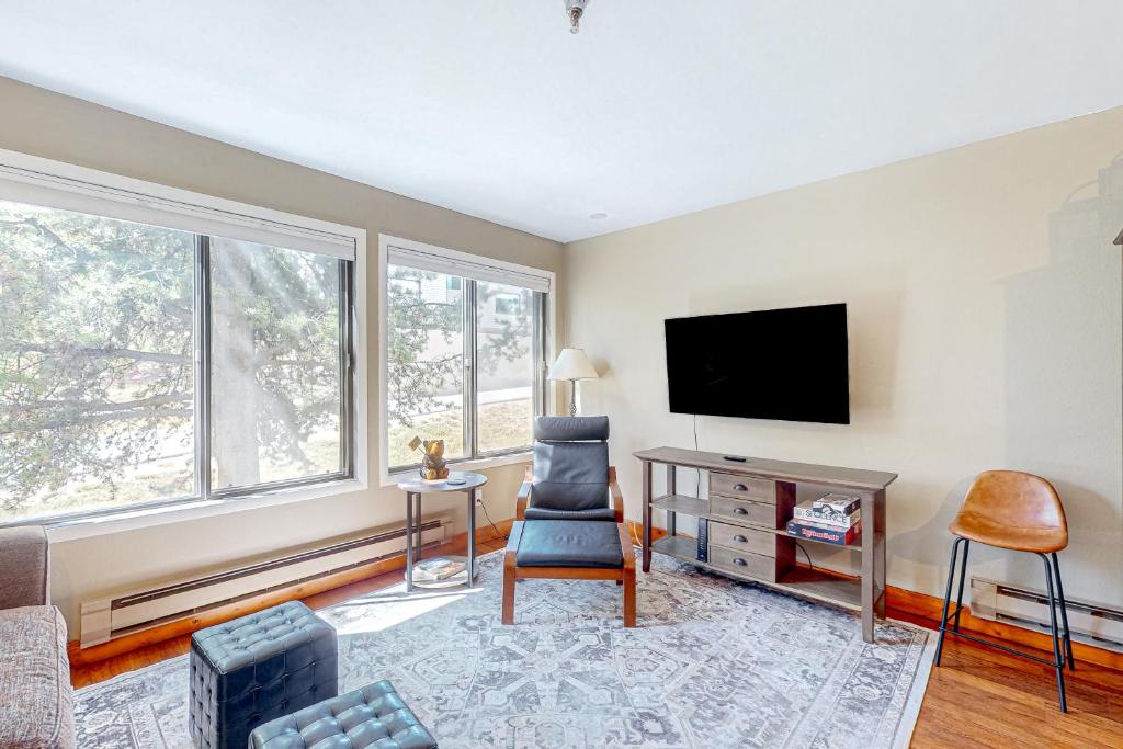 a living room with a tv and a chair at Main Street Retreat in Winter Park