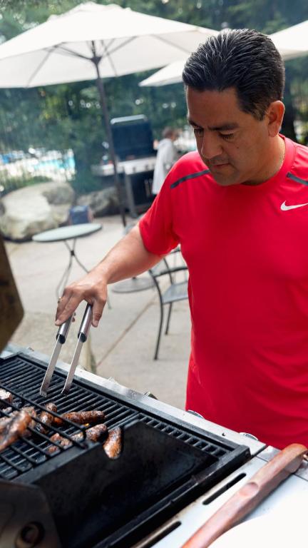 a man is cooking food on a grill at Blackcomb Springs Suites by CLIQUE in Whistler