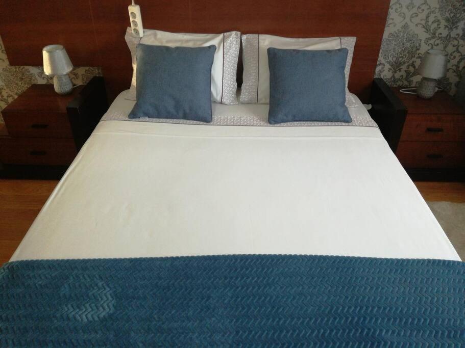 een groot bed met blauwe kussens erop bij Apartamento da Aldeia in Montijo